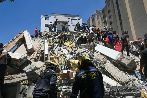 Cali firefighters climbing the rubble of a collapsed building