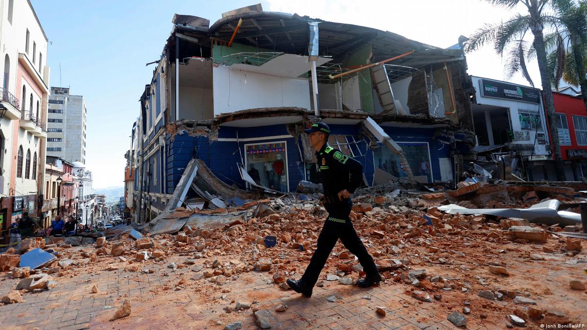 Police officer walking past a collapsed building and rubble on a street in western Colombia