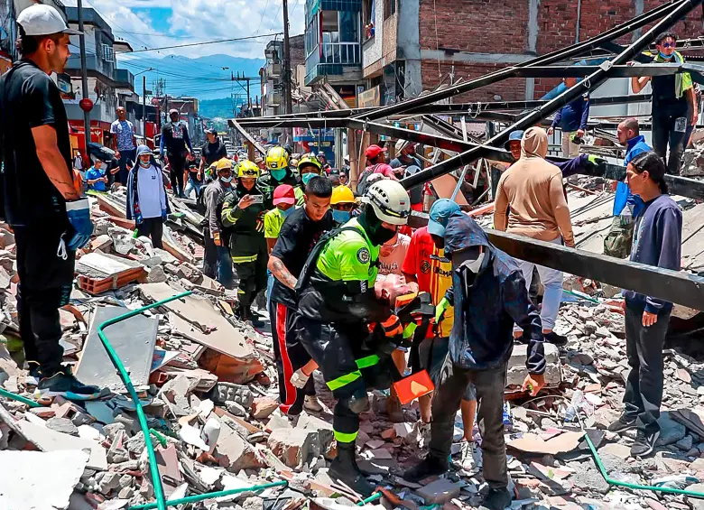 Rescue workers carrying a rescued person on a stretcher through the rubble
